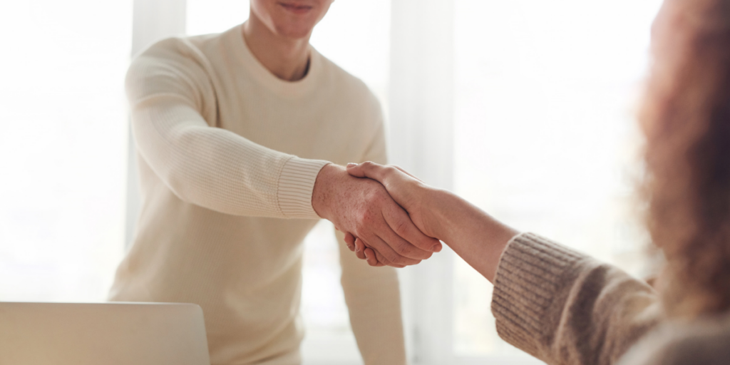 A man shaking hands with a woman across a table.