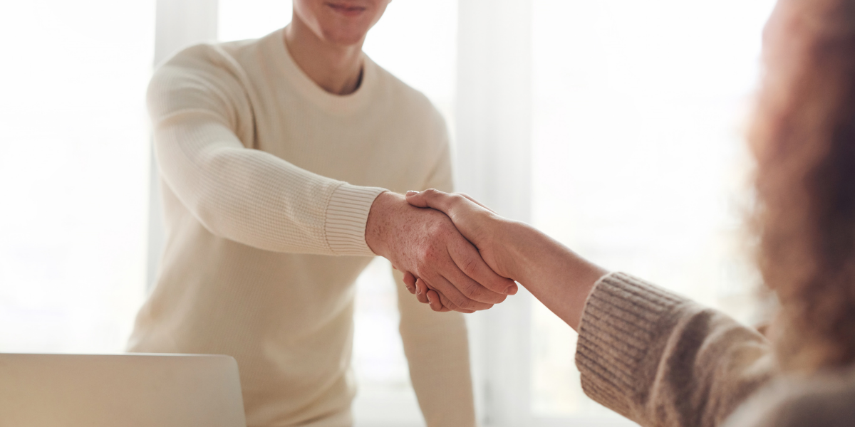 A man shaking hands with a woman across a table.