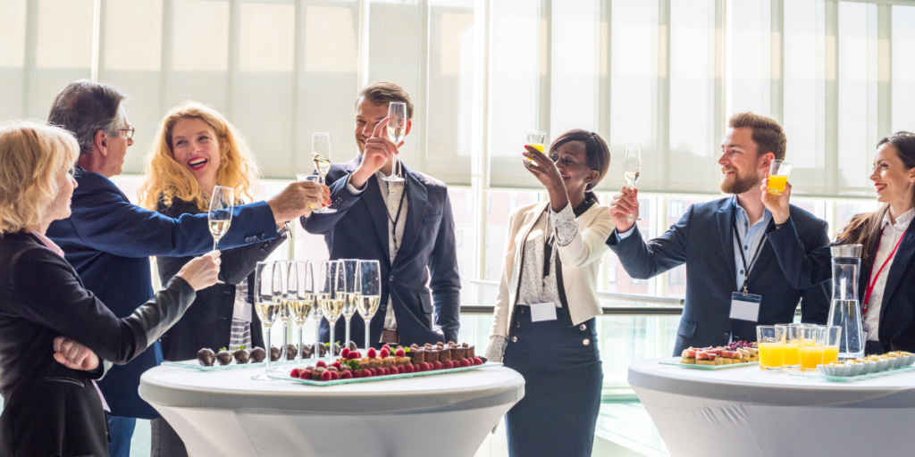 A team of people are stood at a networking session celebrating with champagne.