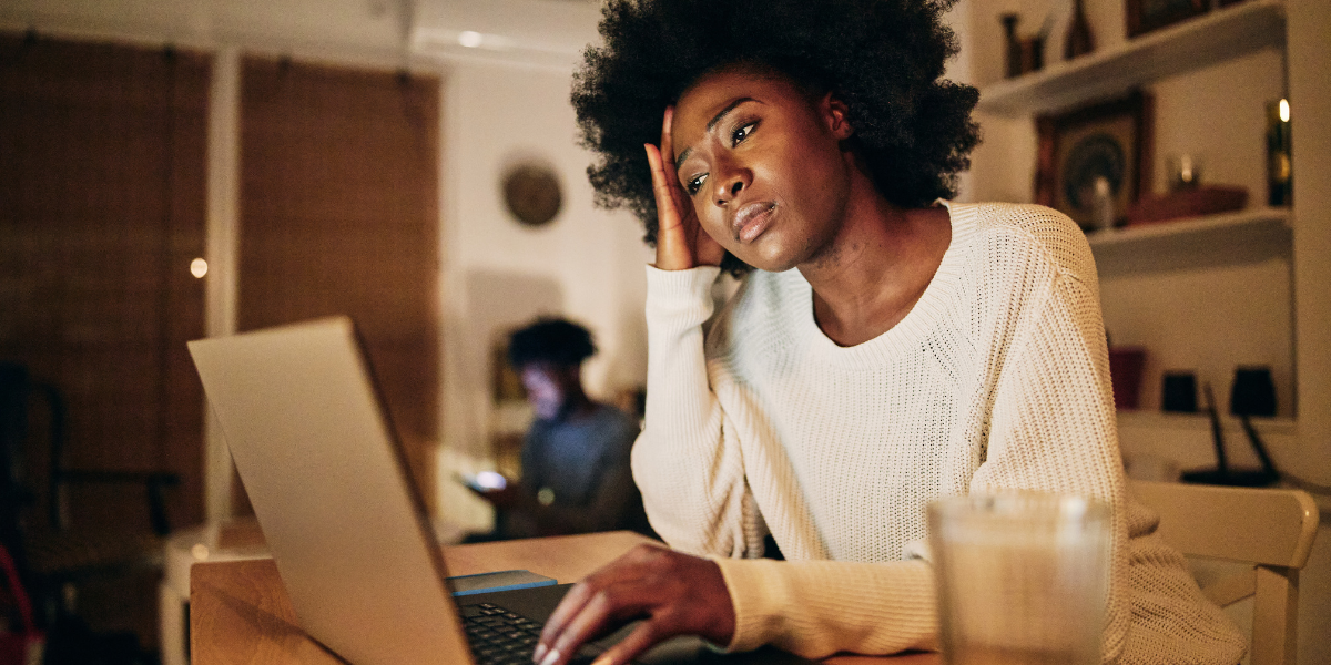 A woman sat at a computer resting her hand on her head.