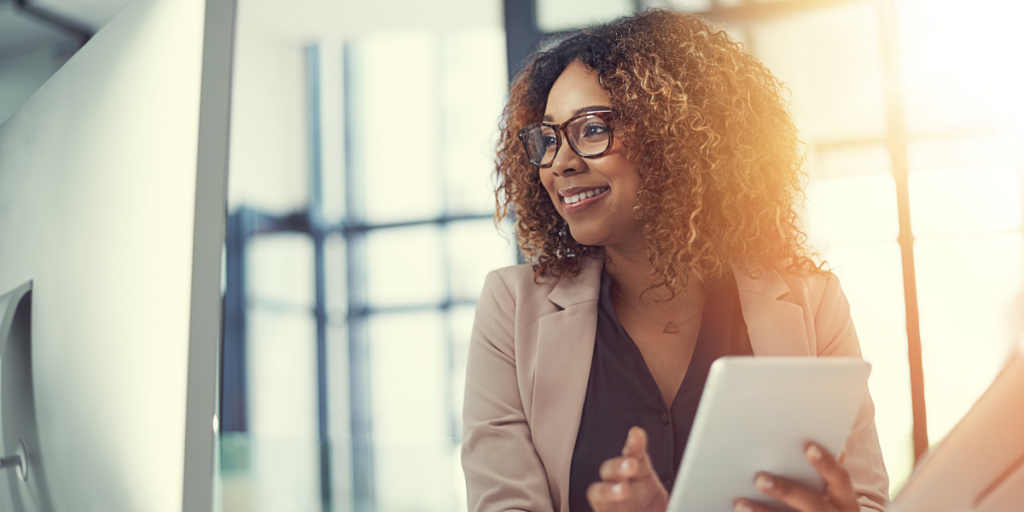 A woman holding a tablet and smiling at the camera.