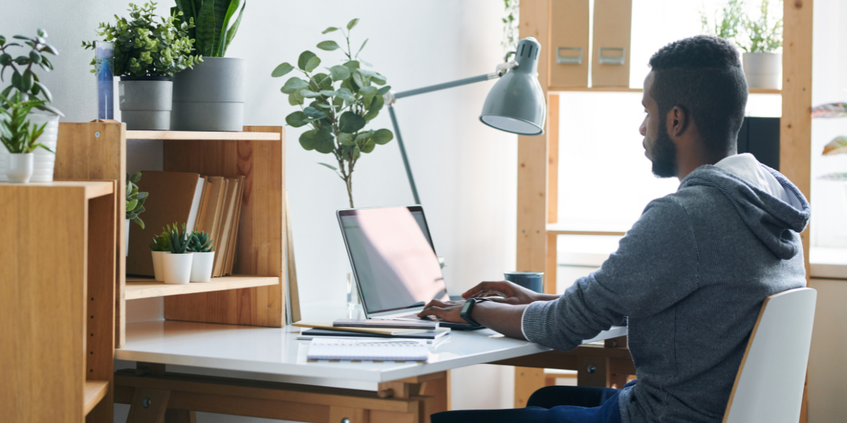 A man sitting at a desk typing on a laptop.