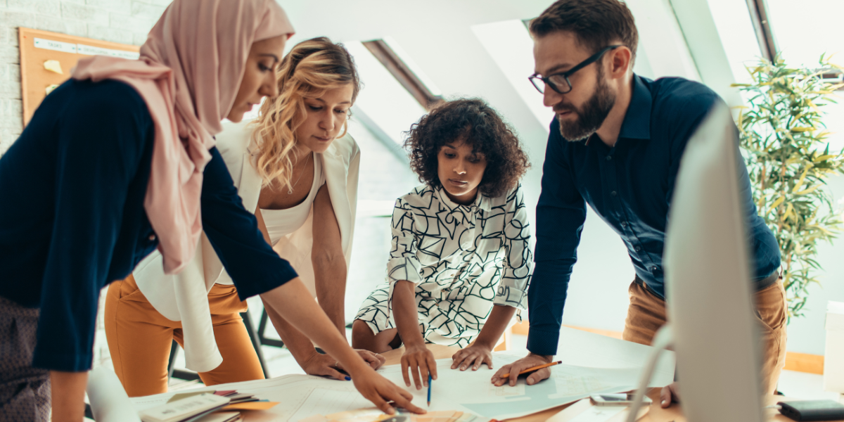 A group of individuals standing around a table working on a document.