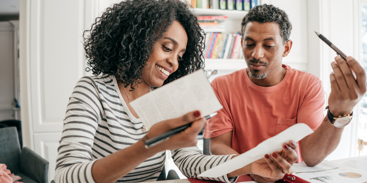 Two people are sitting in their office reviewing paperwork and conversing.