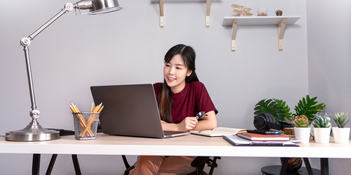 A woman is sitting at a desk working on her laptop.