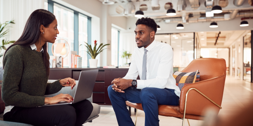 Two people are sat across from each other in an office conversing.