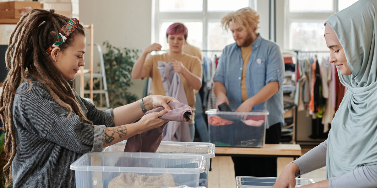 Volunteers working at a clothing drive folding clothes and packaging them.