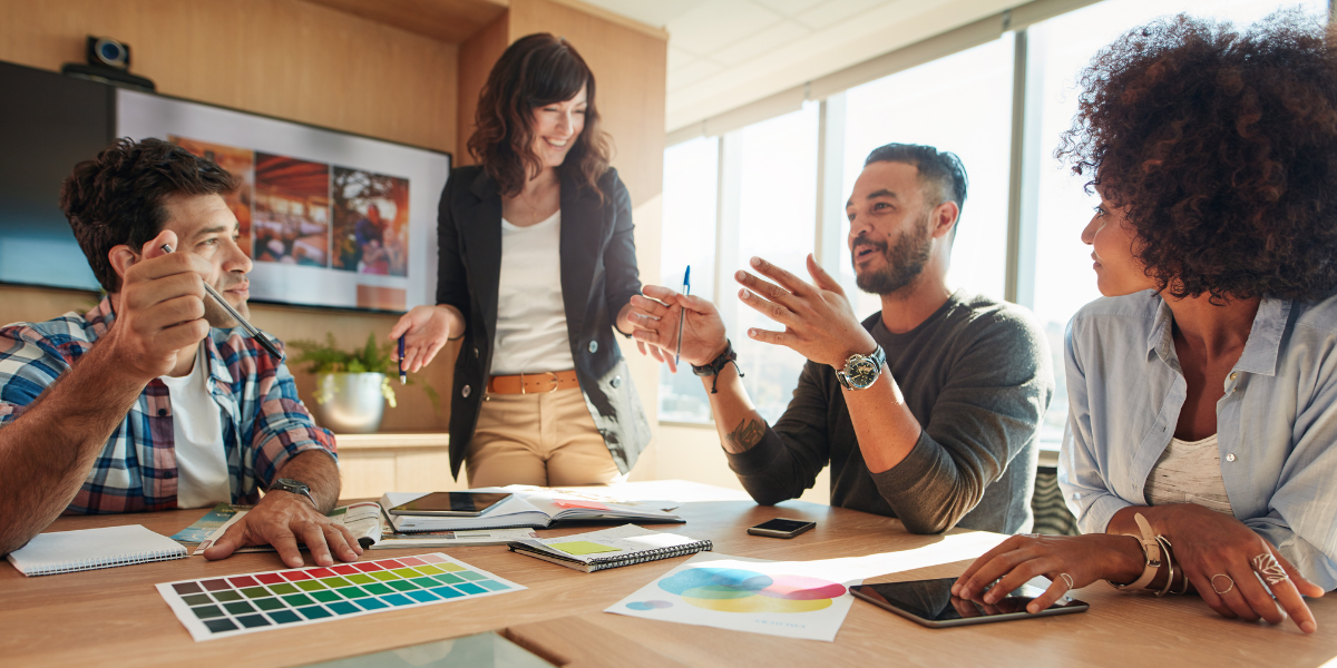 Four people in a boardroom are collaborating on a project.
