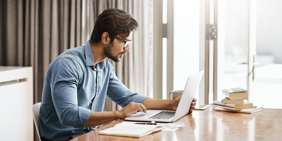 A man sitting in a well-lit office working on a laptop.