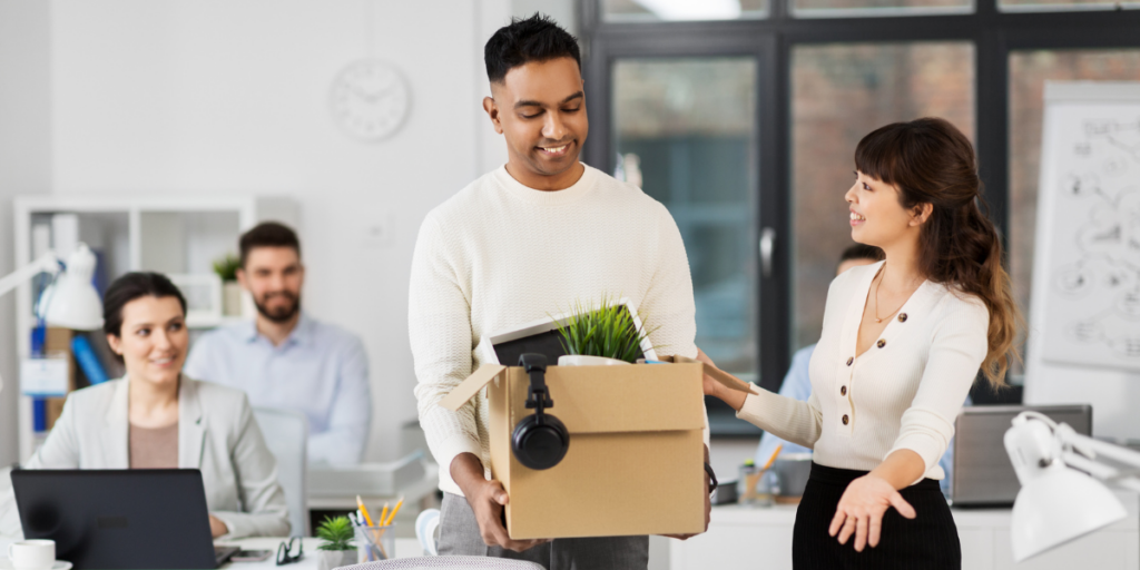 A person with their desk items being welcomed into an office space.
