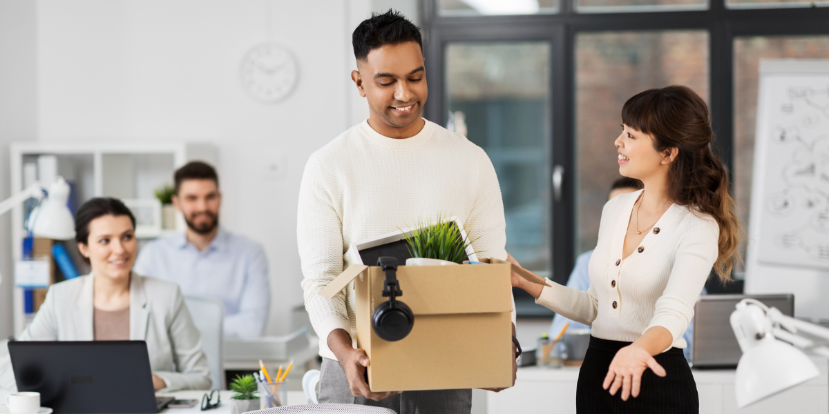 A person with their desk items being welcomed into an office space.