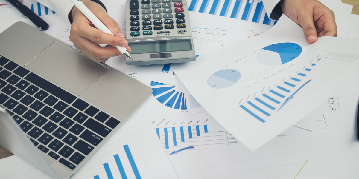 A person sitting at their desk reviewing financial documents and taking notes.