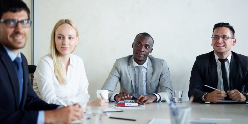 Four people sat at a boardroom table conversing.