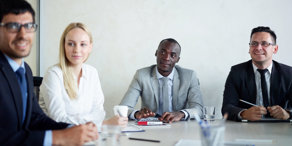 Four people sat at a boardroom table conversing.