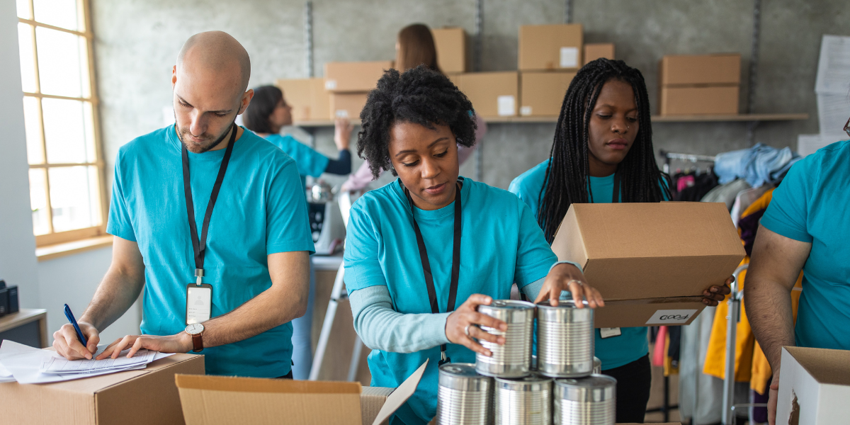A group of volunteers wearing matching blue shirts volunteering at a food bank.