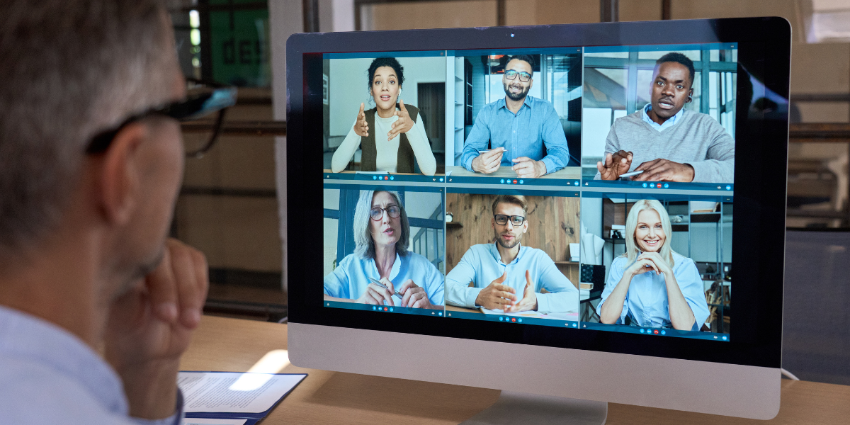 A man sitting at his desk in front of a computer monitor participating in a virtual meeting.