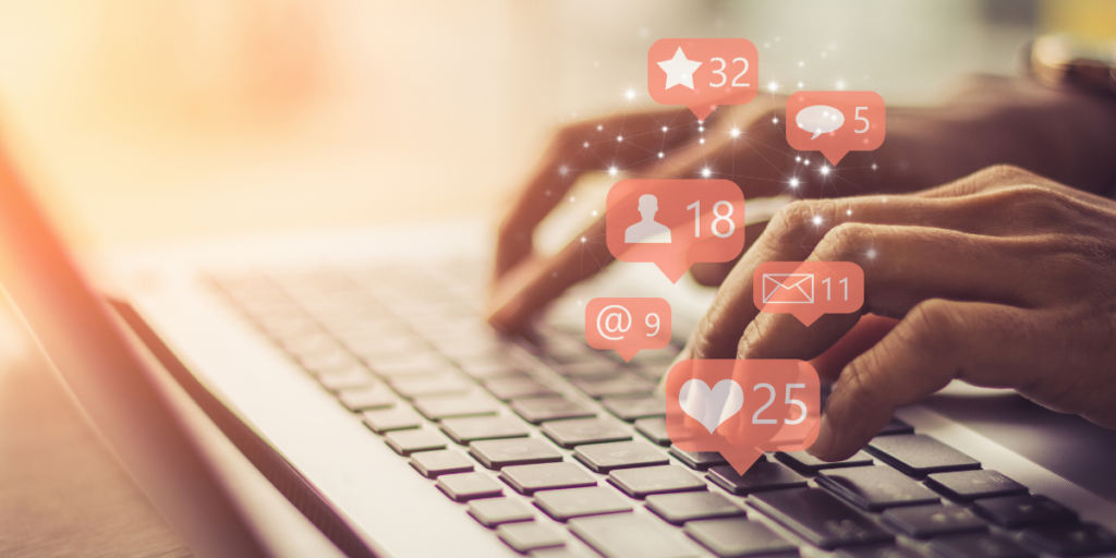 An individual typing on their laptop while social icons and elements are printed on the screen overlapping the background image.