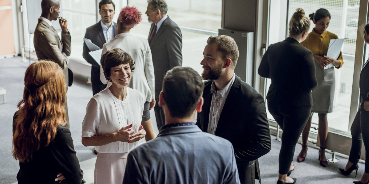 A group of people in business casual in an office space networking.