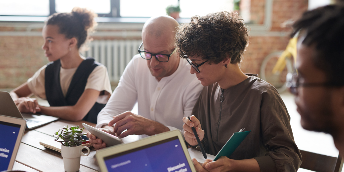 A group of individuals sat at a boardroom table conversing.