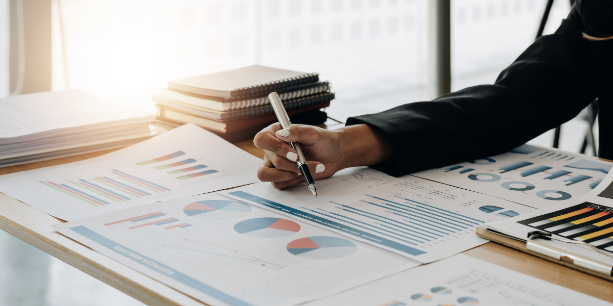 A woman sitting at a desk writing on financial documents.