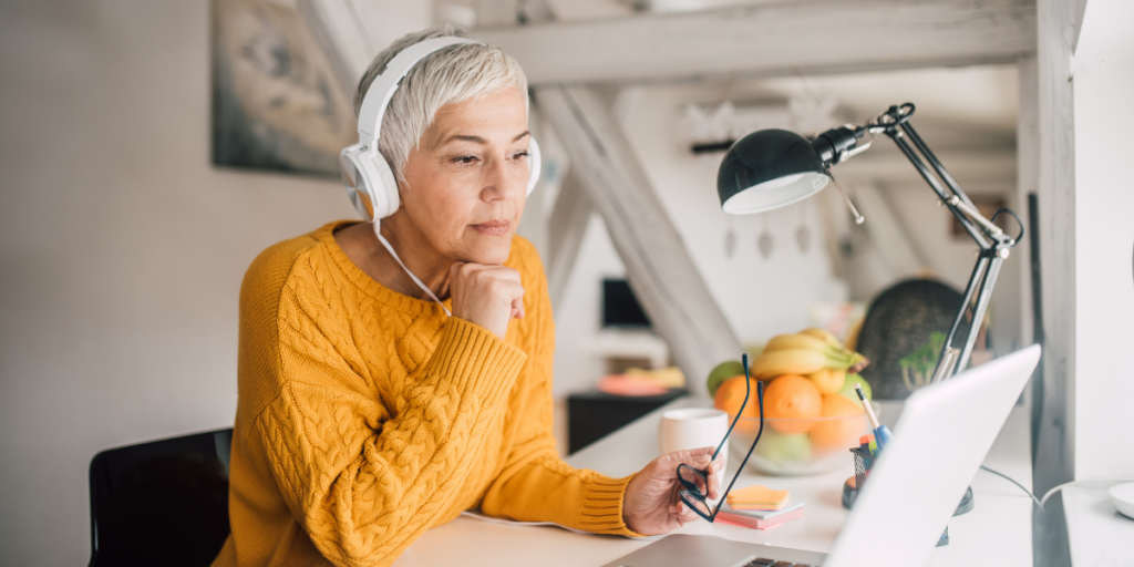 An older woman sitting at her desk looking at her laptop.