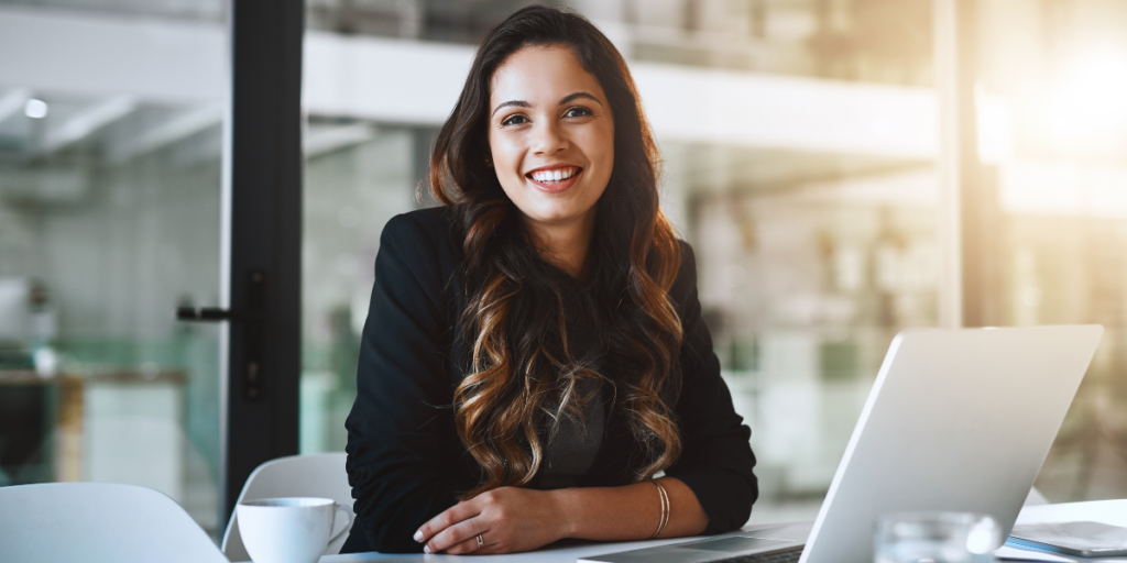 A woman smiling staring at the camera wearing a black blouse.