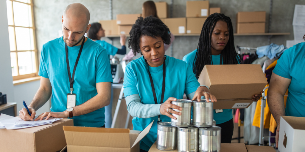 A group of volunteers wearing matching blue shirts volunteering at a food bank.