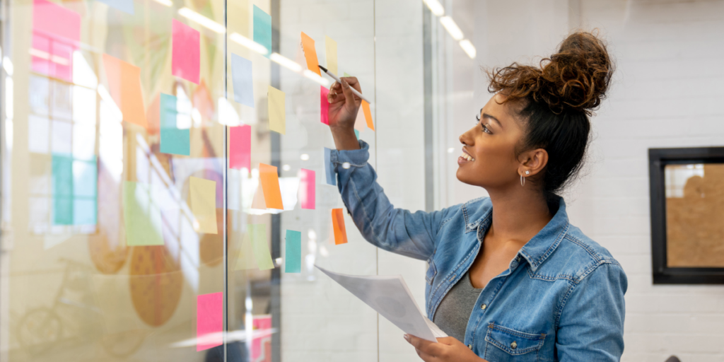 A woman stood at a white board writing notes.