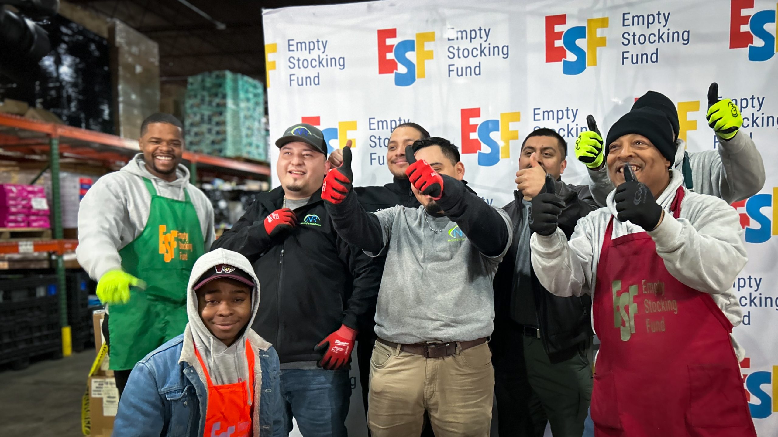 A group of individuals from the Empty Stocking Fund are stood celebrating in front of the camera.