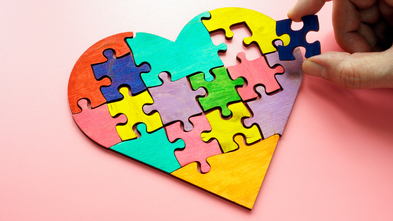 A heart puzzle with varying colours on a pink table.