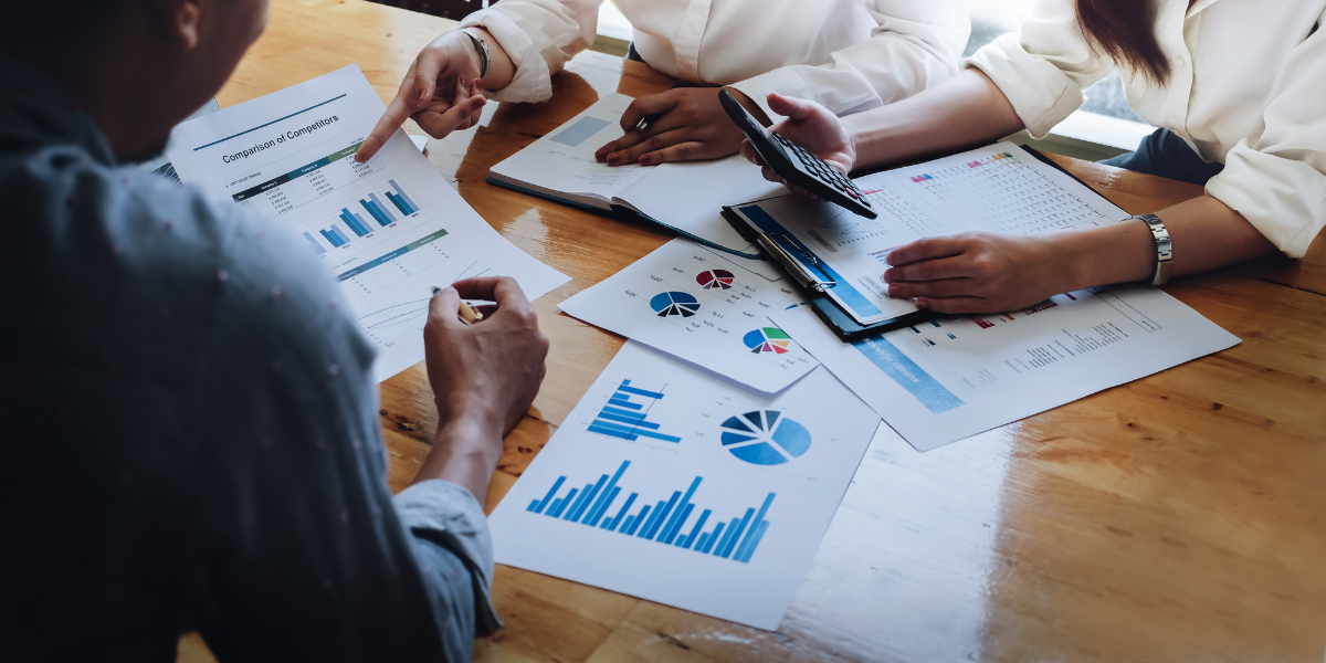 Three people sitting at a boardroom table reviewing financial data.