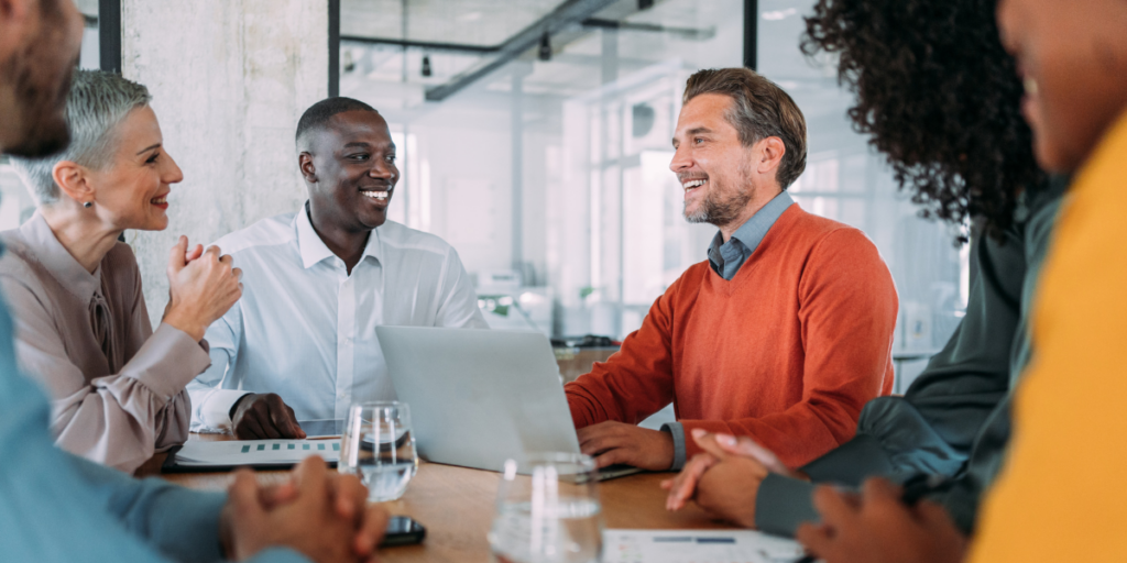 A group of people sat at a boardroom table in an office having a meeting.