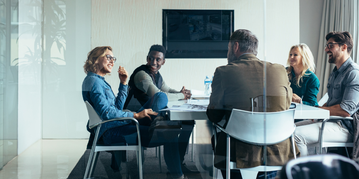 Five people are sitting at a boardroom table discussing.