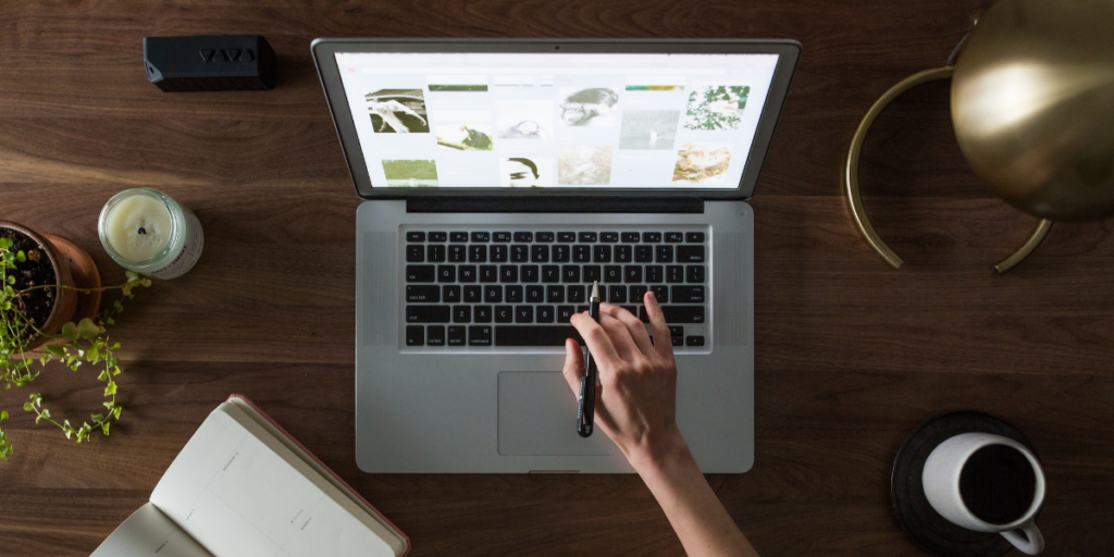 A person typing on their laptop with a latte next to them.