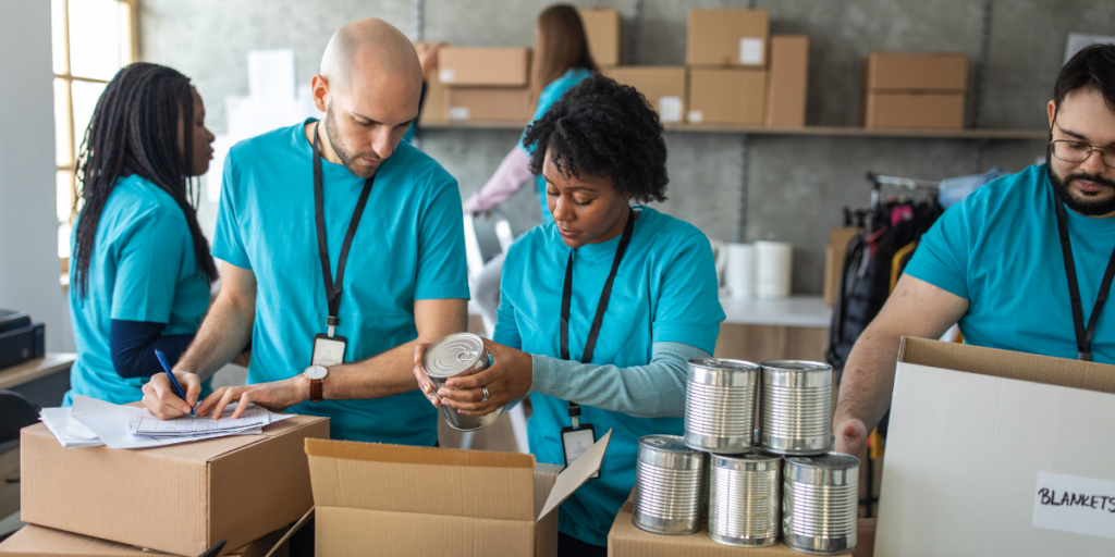 Volunteers wearing blue shirts are working in a food bank and packing preserves.