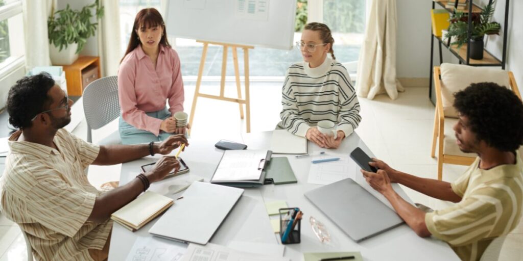 Four people are sat at a boardroom table working.