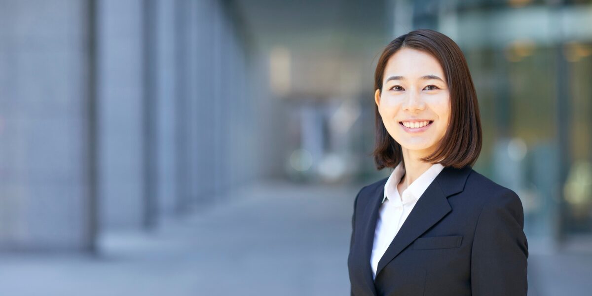 A woman is stood smiling at the camera in a business centre.