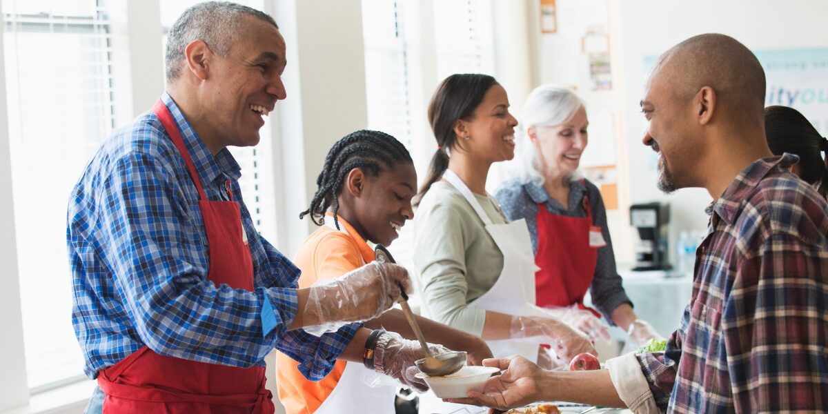 A group of people are volunteering at a food bank and serving soup.