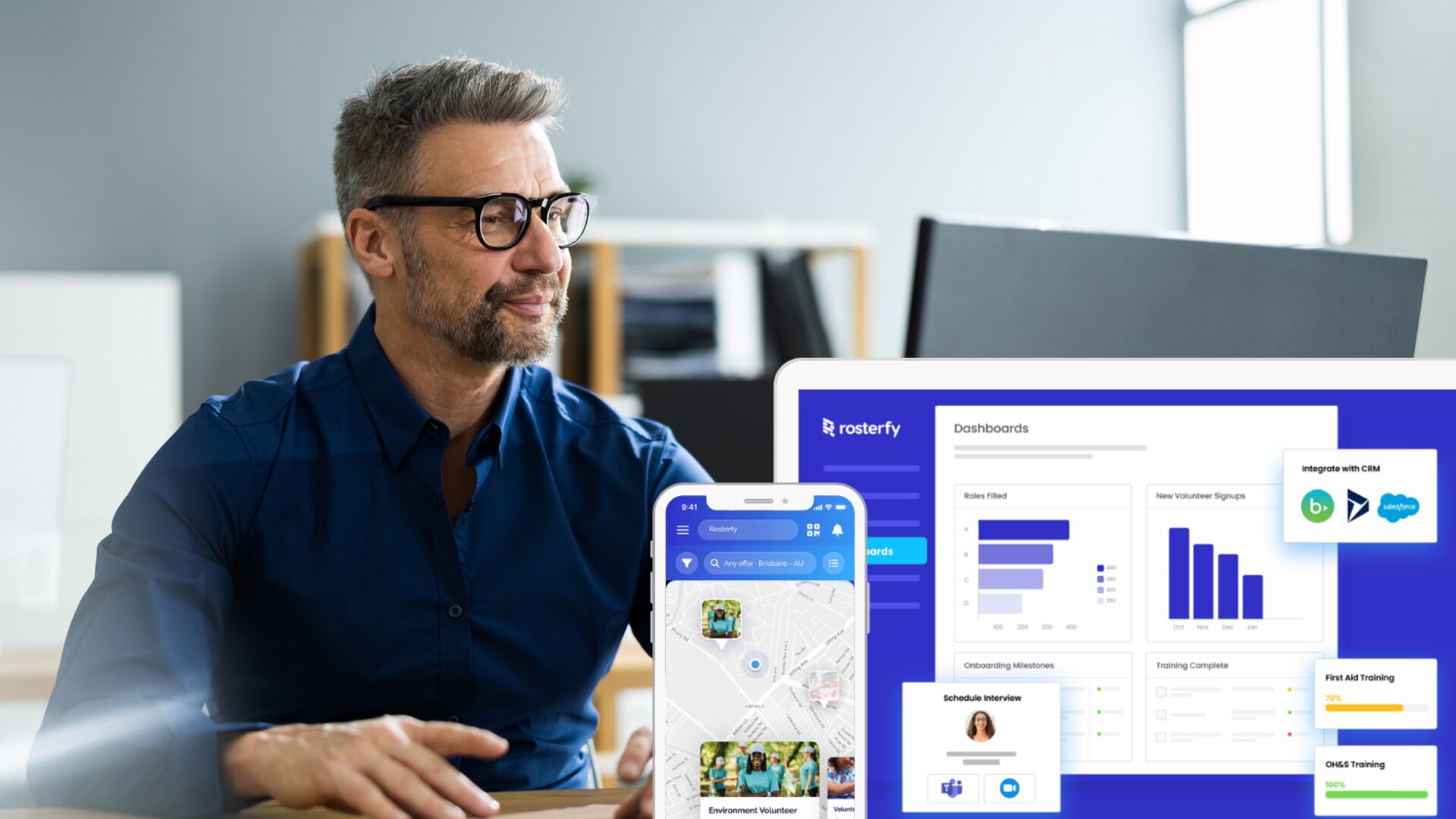 A man is sat at his desk working and reviewing the Rosterfy branded dashboard.