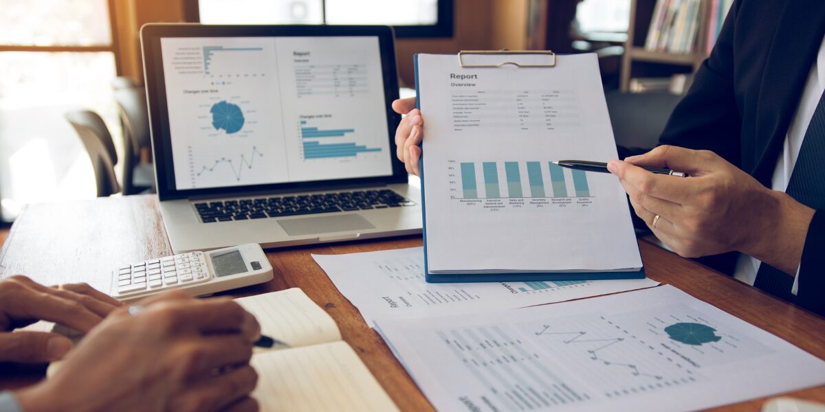 Two people are sat at a desk reviewing financial reports.