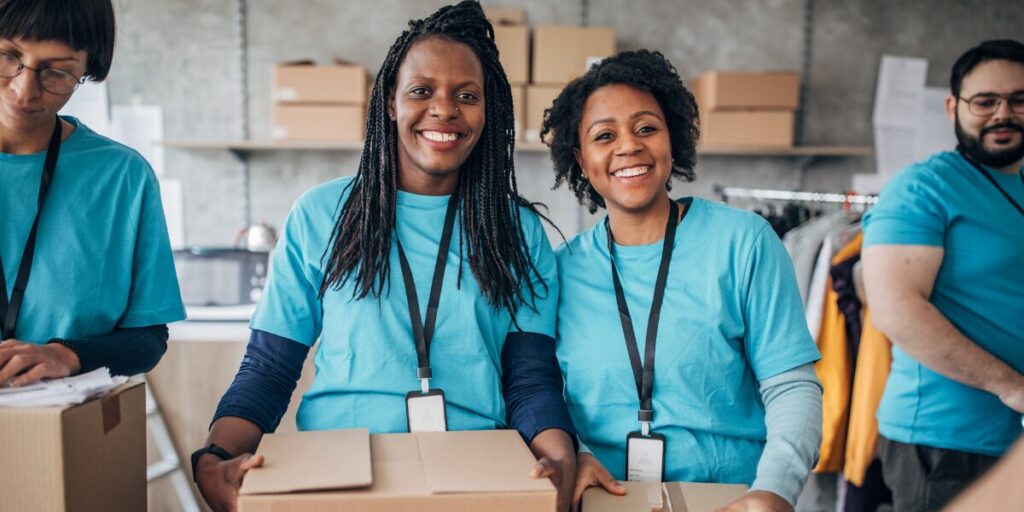 Volunteers are smiling and packaging care boxes at a food bank.