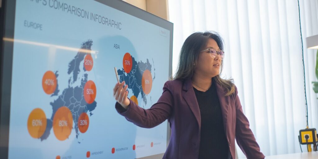 A woman is stood presenting data to colleagues.