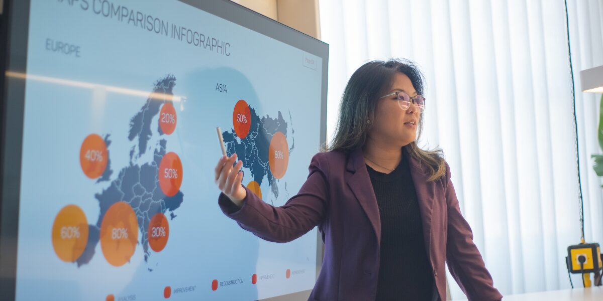 A woman is stood presenting data to colleagues.