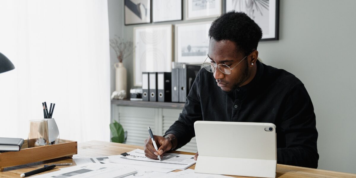A man is sitting at his desk taking notes and working.