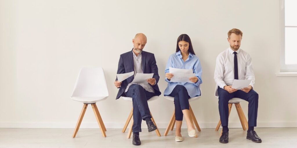 Three people are sat in a row along a wall reviewing documents.