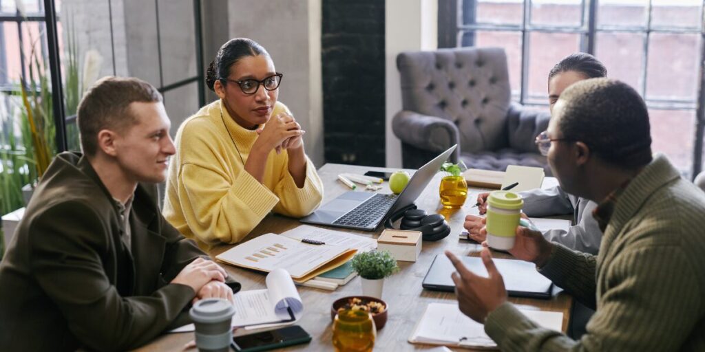 A group of four people are sat around a boardroom table working.